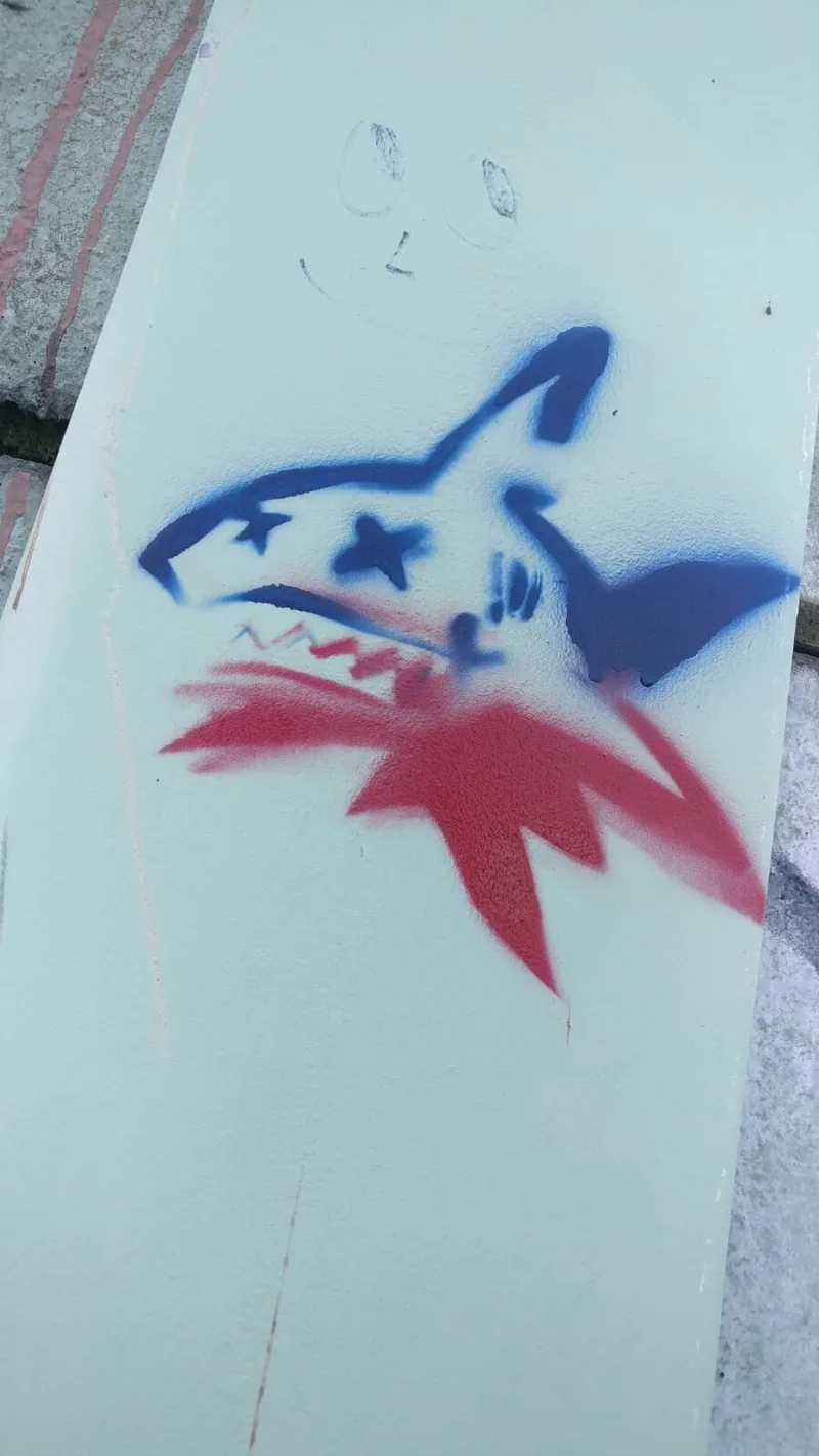 A blue shark with a red star painted on a white surface.