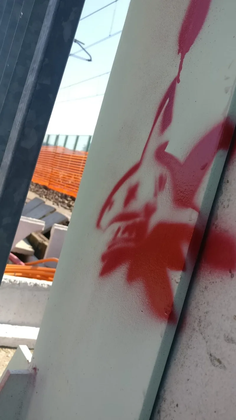 A red spray tag on a rough concrete wall.